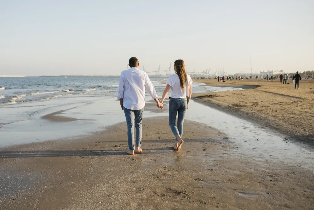 Junges Paar spaziert am Strand entlang des Meeres